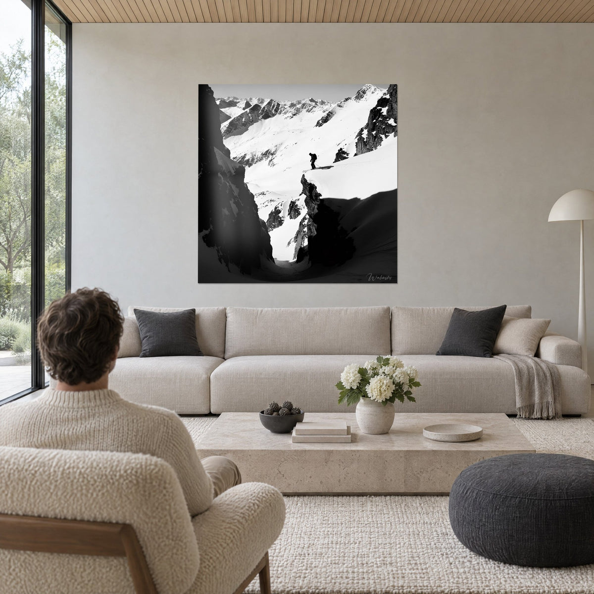 Tableau skieur en silhouette sur une arête de neige blanche, couloir rocheux noir, crêtes lointaines, au-dessus d'un canapé dans un salon lumineux