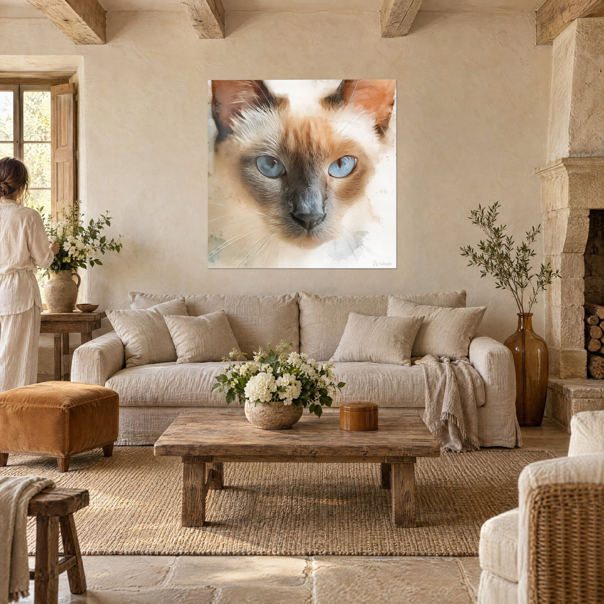 Schilderij Siamese kat met blauwe ogen in aquarel, crème en rossige vacht, twee personen van achteren boven een bank in een lichte woonkamer