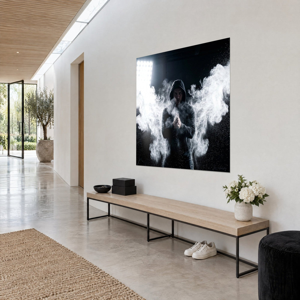 Wall art of a sporty figure in a black hoodie with white powder wings spread and a blazing spotlight, hung at an angle on a cream wall