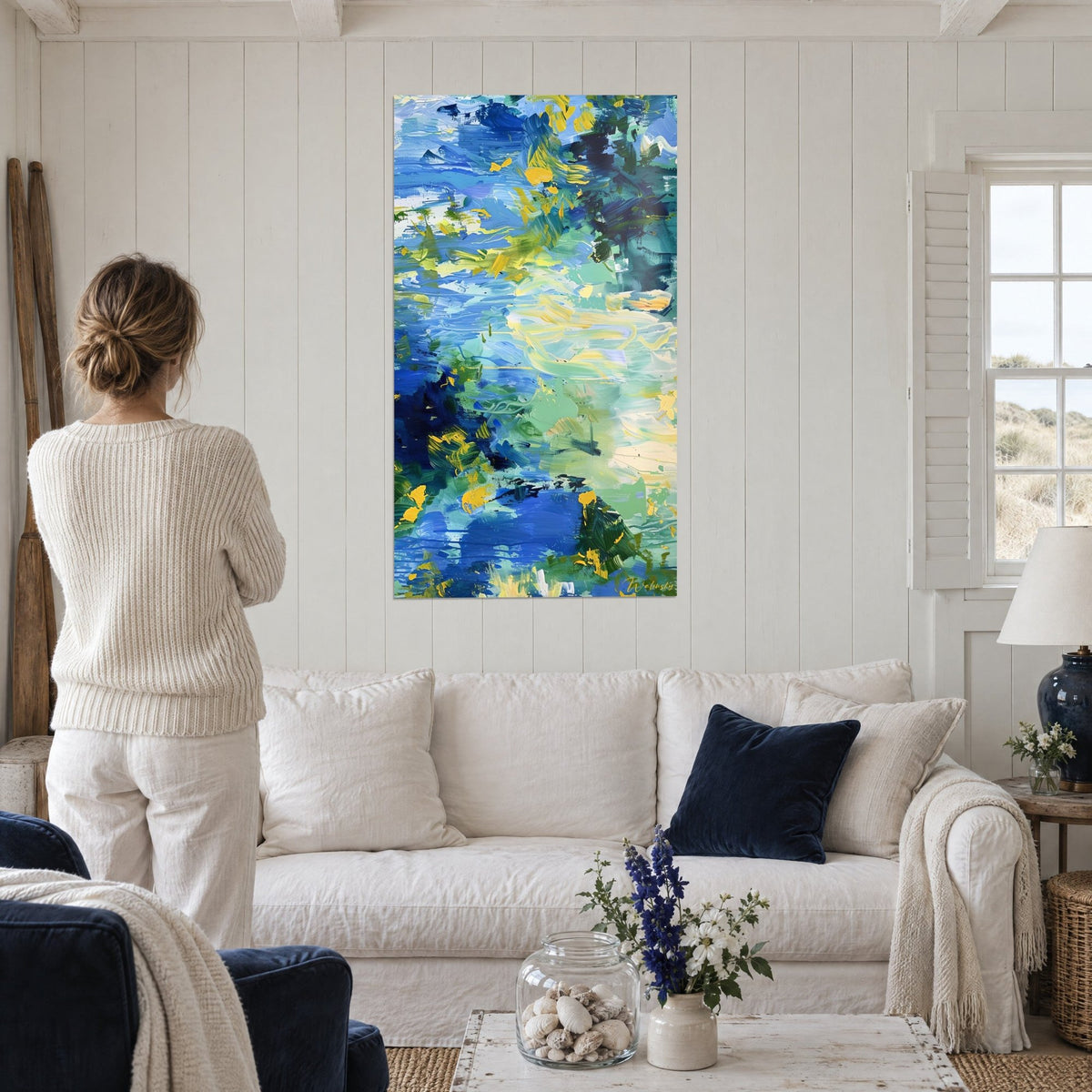 Tableau coups de pinceau bleu cobalt et jaune d'or, eau abstraite, femme de dos, au-dessus d'un canapé dans un salon lumineux