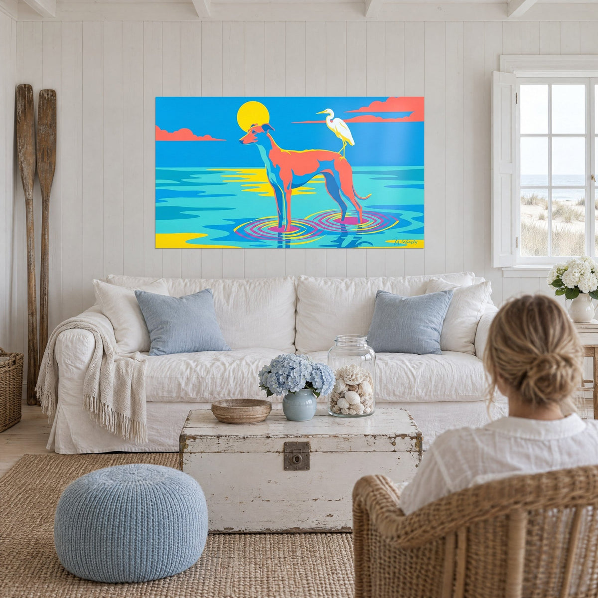 Gemälde Windhund Koralle im türkisfarbenen Wasser, gelbe Sonne und weißer Reiher, über einem Sofa in einem hellen Wohnzimmer