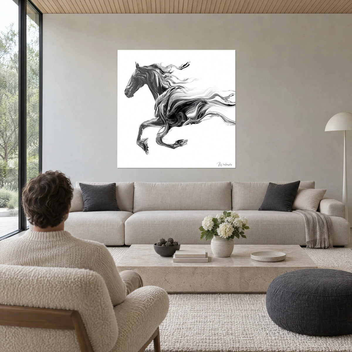 Tableau cheval noir lancé au galop, crinière en rubans gris sur fond blanc, homme de dos, au-dessus d'un canapé dans un salon lumineux
