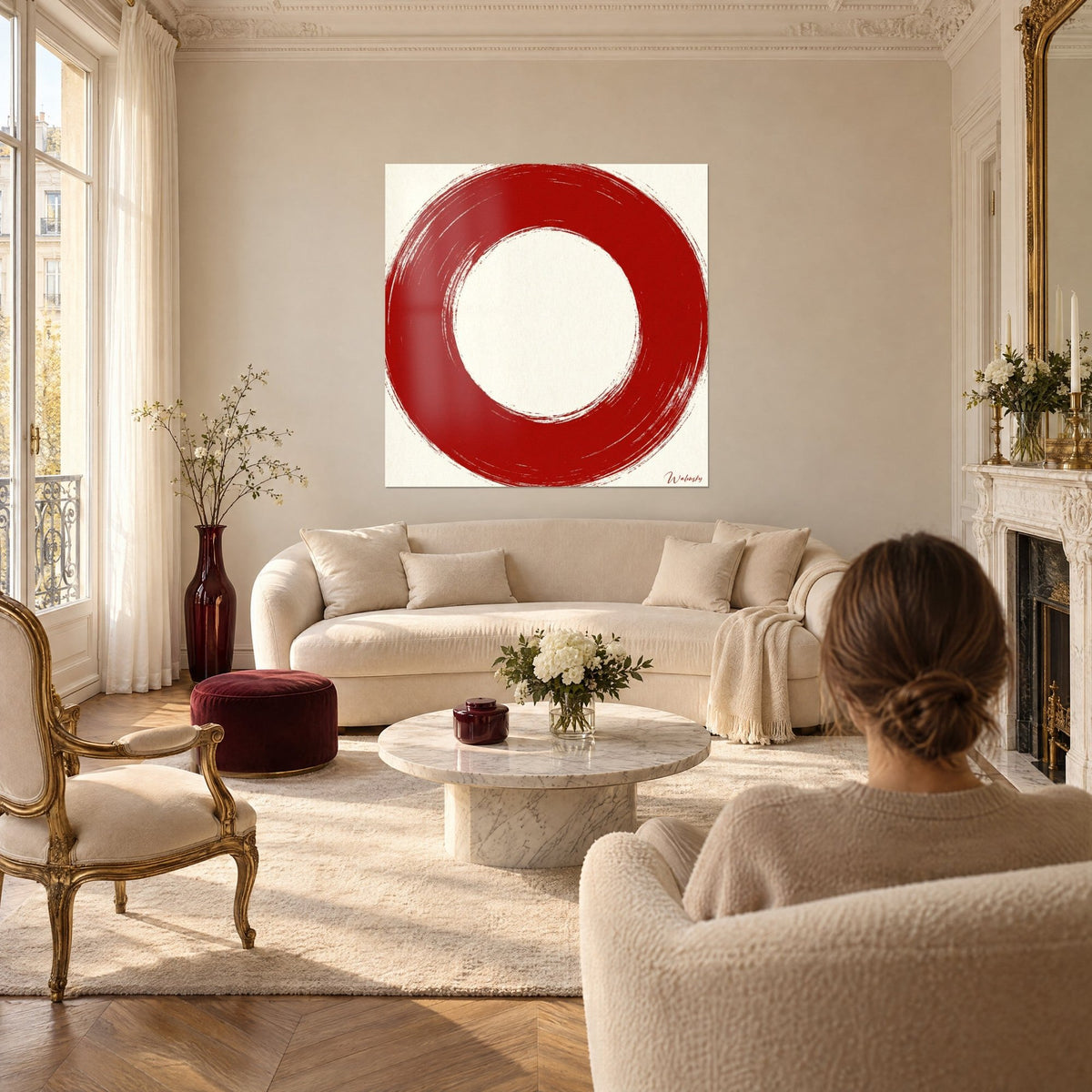 Quadro cerchio rosso carminio tracciato a pennello su fondo crema, una donna di spalle, sopra un divano in un soggiorno luminoso