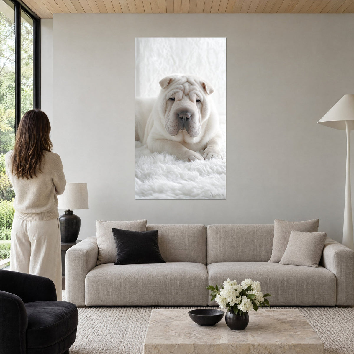 Cuadro shar pei color crema con pliegues profundos, hocico gris rosado, sobre piel blanca; mujer de espaldas encima de un sofá en un salón luminoso