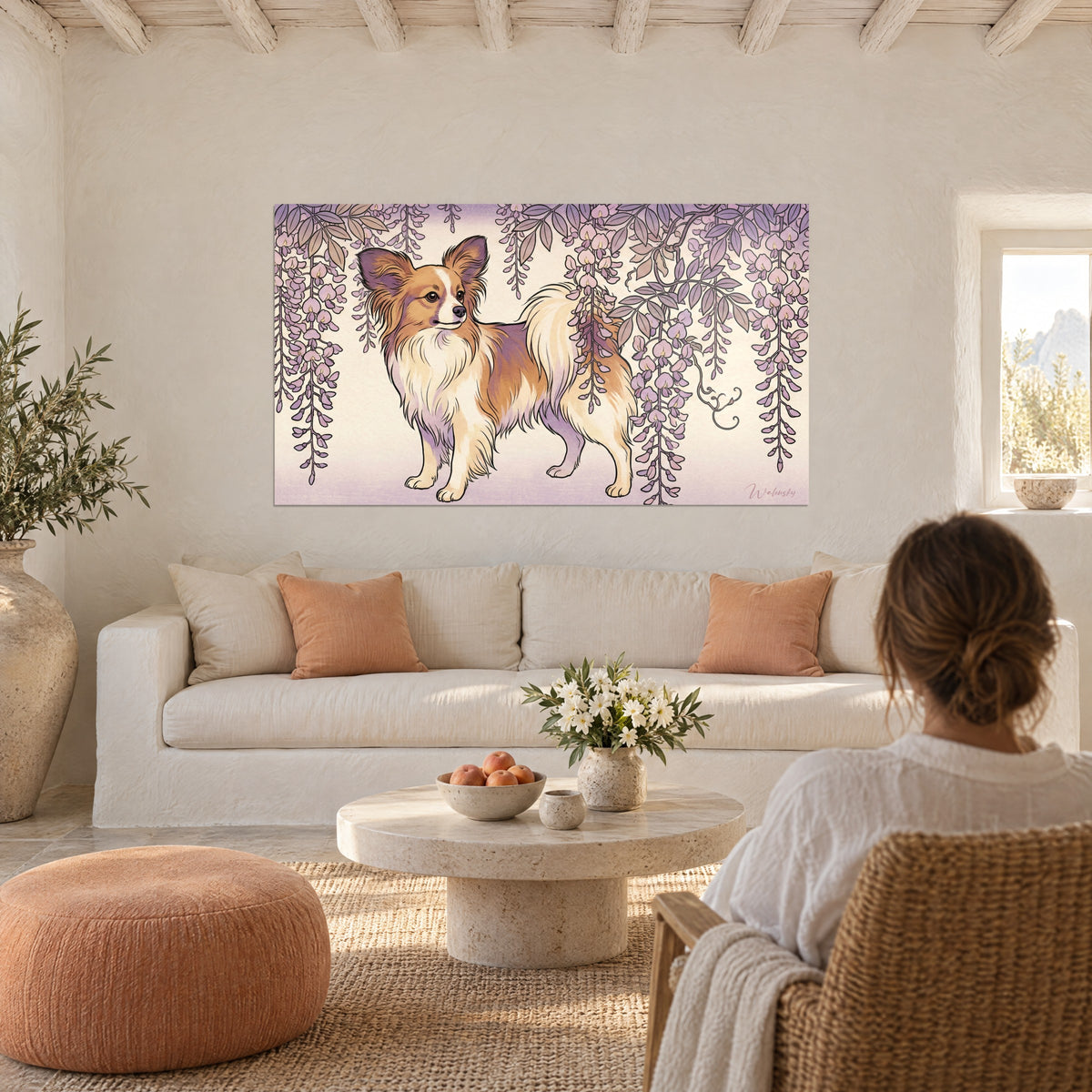 Cuadro de perro papillón de orejas flecadas, pelaje leonado y crema bajo glicinias moradas, sobre un sofá en un salón luminoso