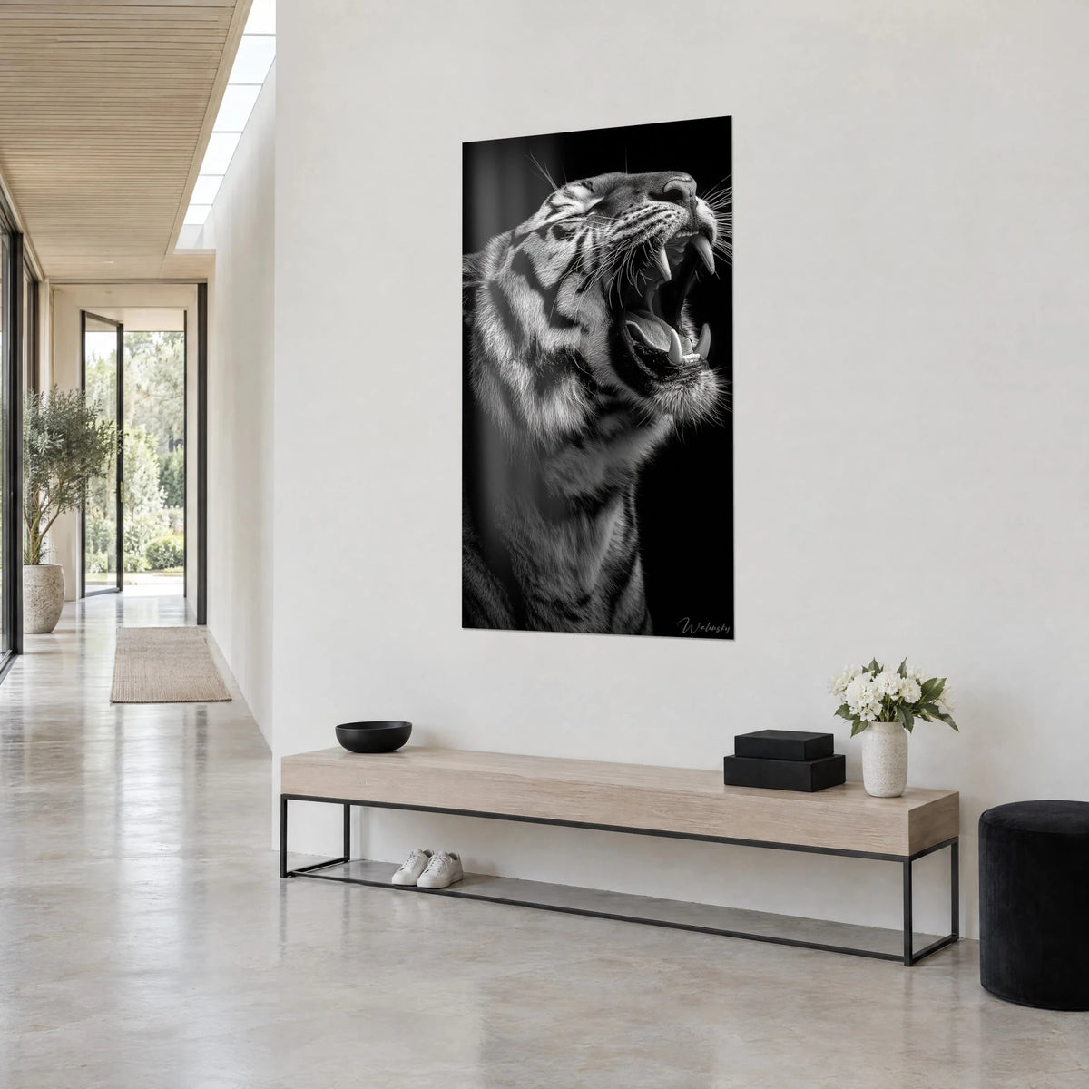 Wall art big cat with open jaws, black stripes and silvery fur, hung on a white wall near a bright hallway