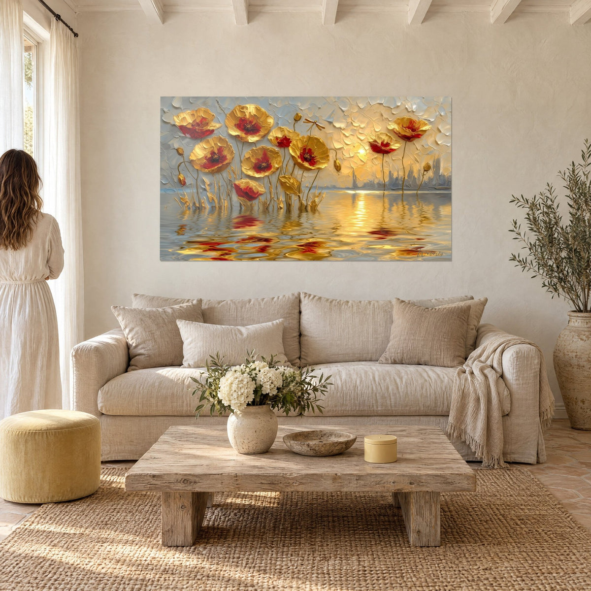 Wall art with embossed golden poppies, carmine red hearts on a pearl grey background, woman seen from behind, above a sofa in a bright living room