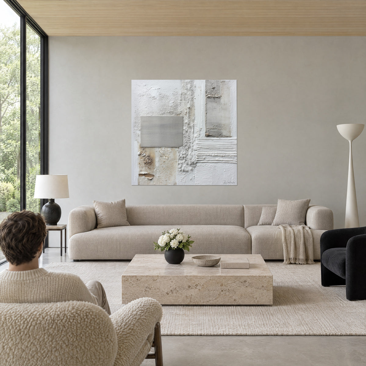 Schilderij abstracte compositie in krijtwitte reliëfs en beige linnen, twee personen van achteren, boven een bank in een lichte woonkamer