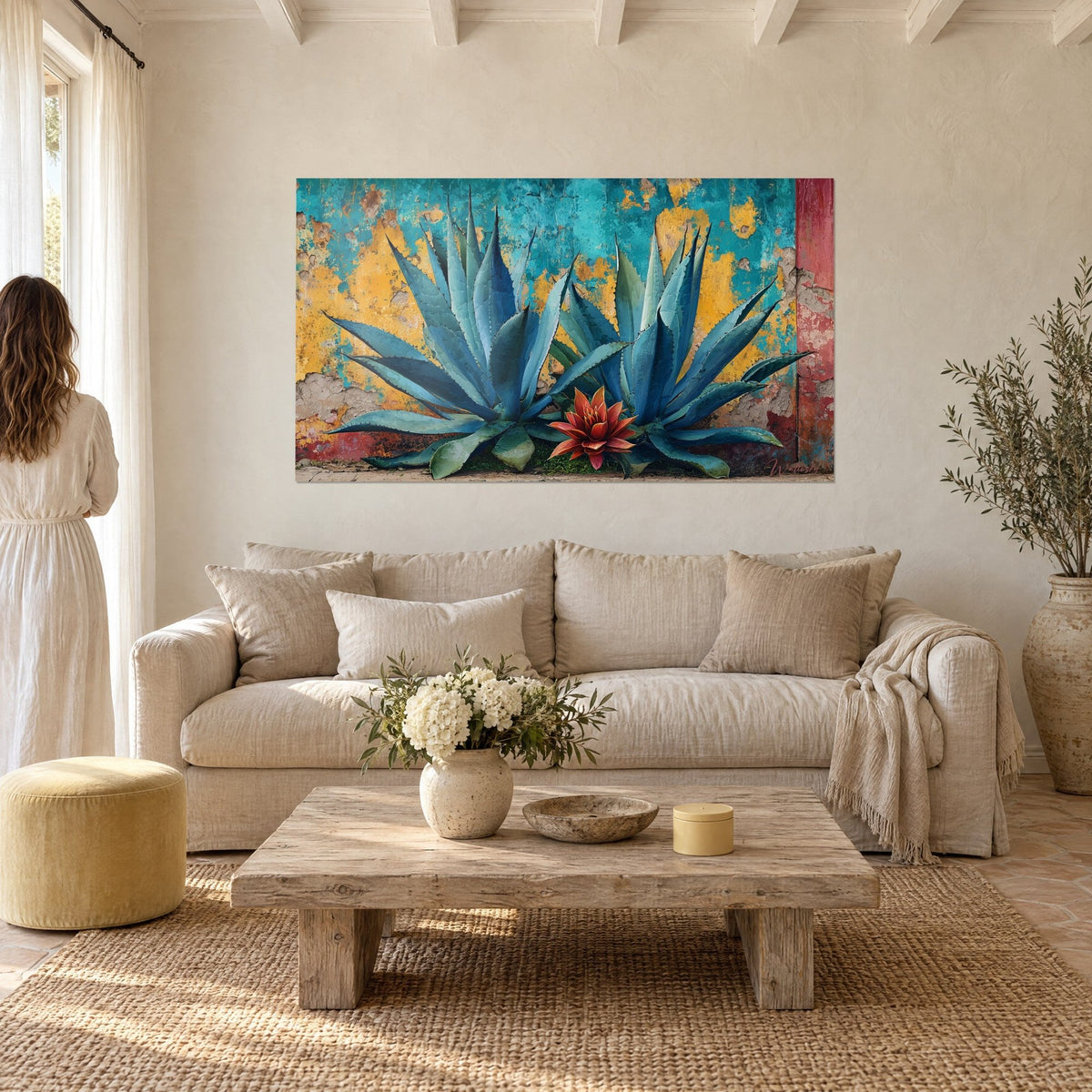 Tableau agaves bleu-vert aux piquants dentelés sur mur turquoise et jaune écaillé, au-dessus d'un canapé dans un salon lumineux