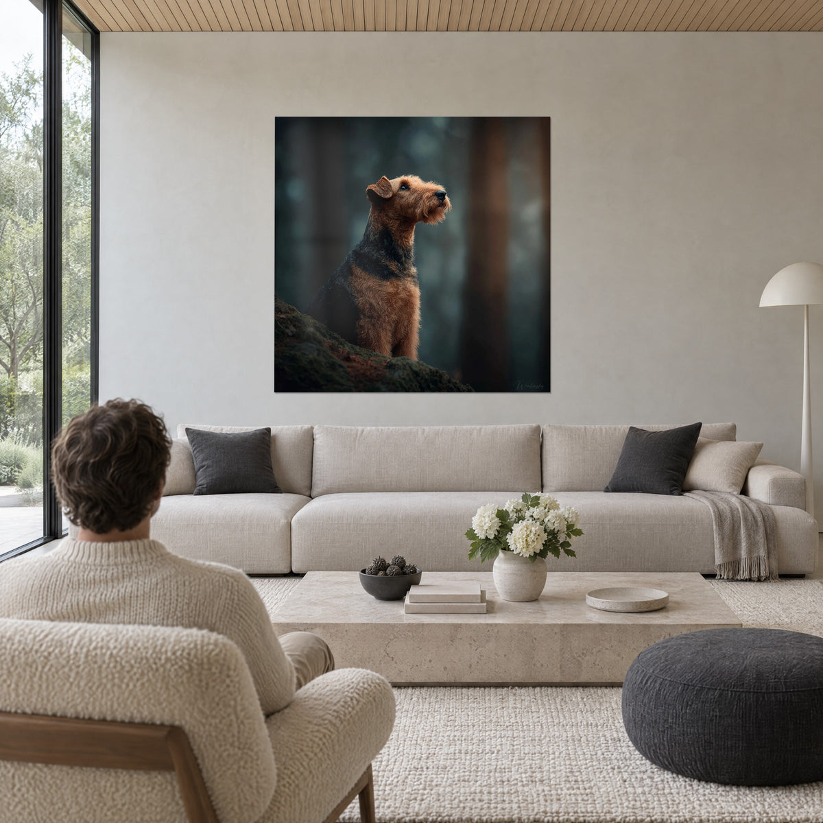 Πίνακας Airedale Terrier με ρόδινο-μαύρο τρίχωμα και ψηλά υψωμένο ρύγχος μέσα σε ομιχλώδες δάσος, πάνω από καναπέ σε φωτεινό σαλόνι