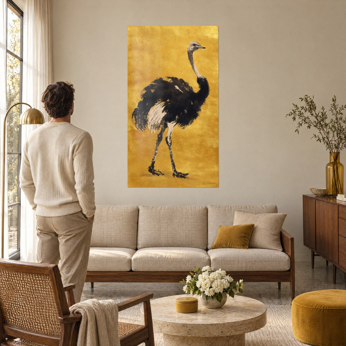 Cuadro avestruz de plumaje negro tinta y plumas crema, sobre fondo dorado, encima de un sofá en un salón luminoso