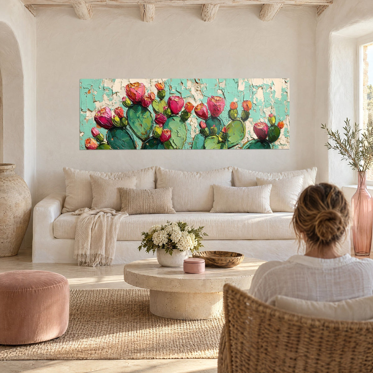 Gemälde Kakteen mit fuchsiafarbenen Blüten auf abblätternd türkisfarbenem Grund, eine Frau von hinten, über einem Sofa in einem hellen Wohnzimmer