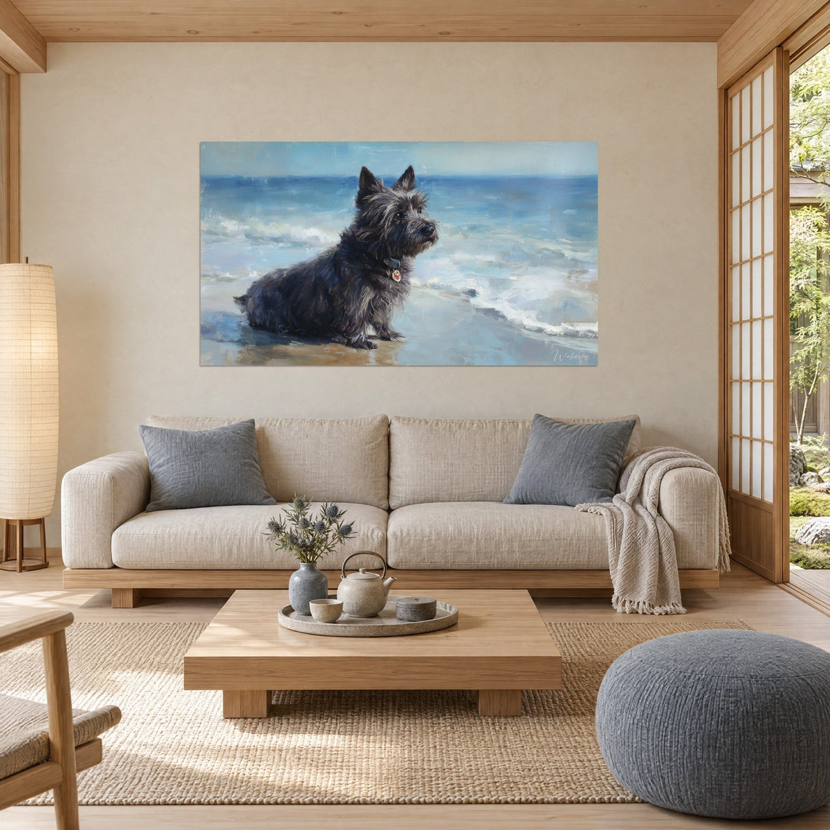 Wall art of a charcoal grey Cairn Terrier sitting facing blue waves, white foam, above a sofa in a bright living room