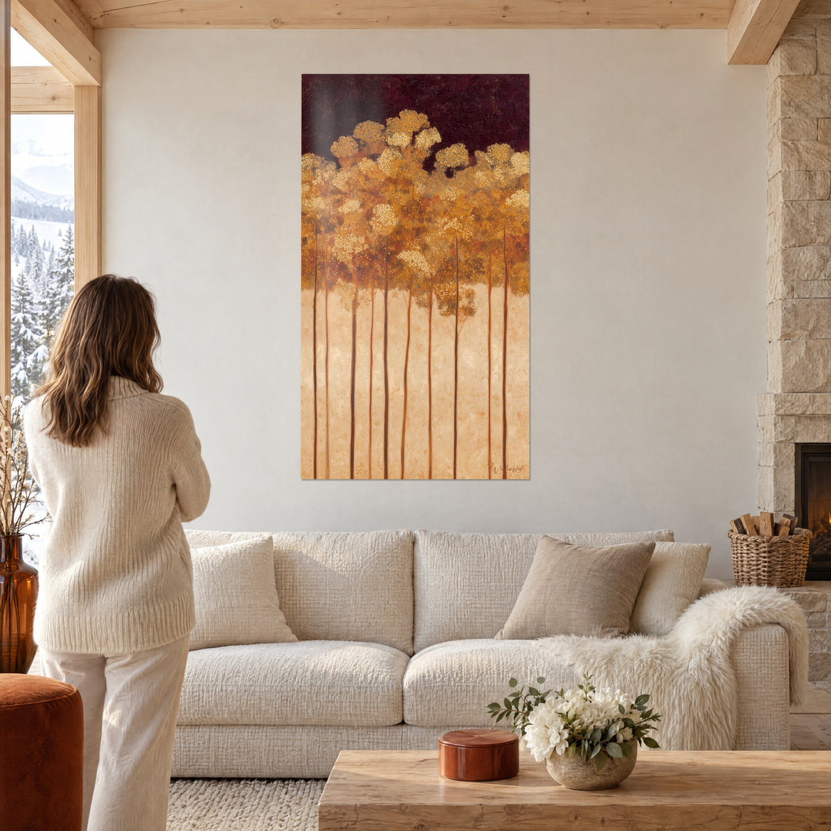 Schilderij gouden bos met slanke stammen op bordeauxrode achtergrond, vrouw van achteren, boven een bank in een lichte woonkamer