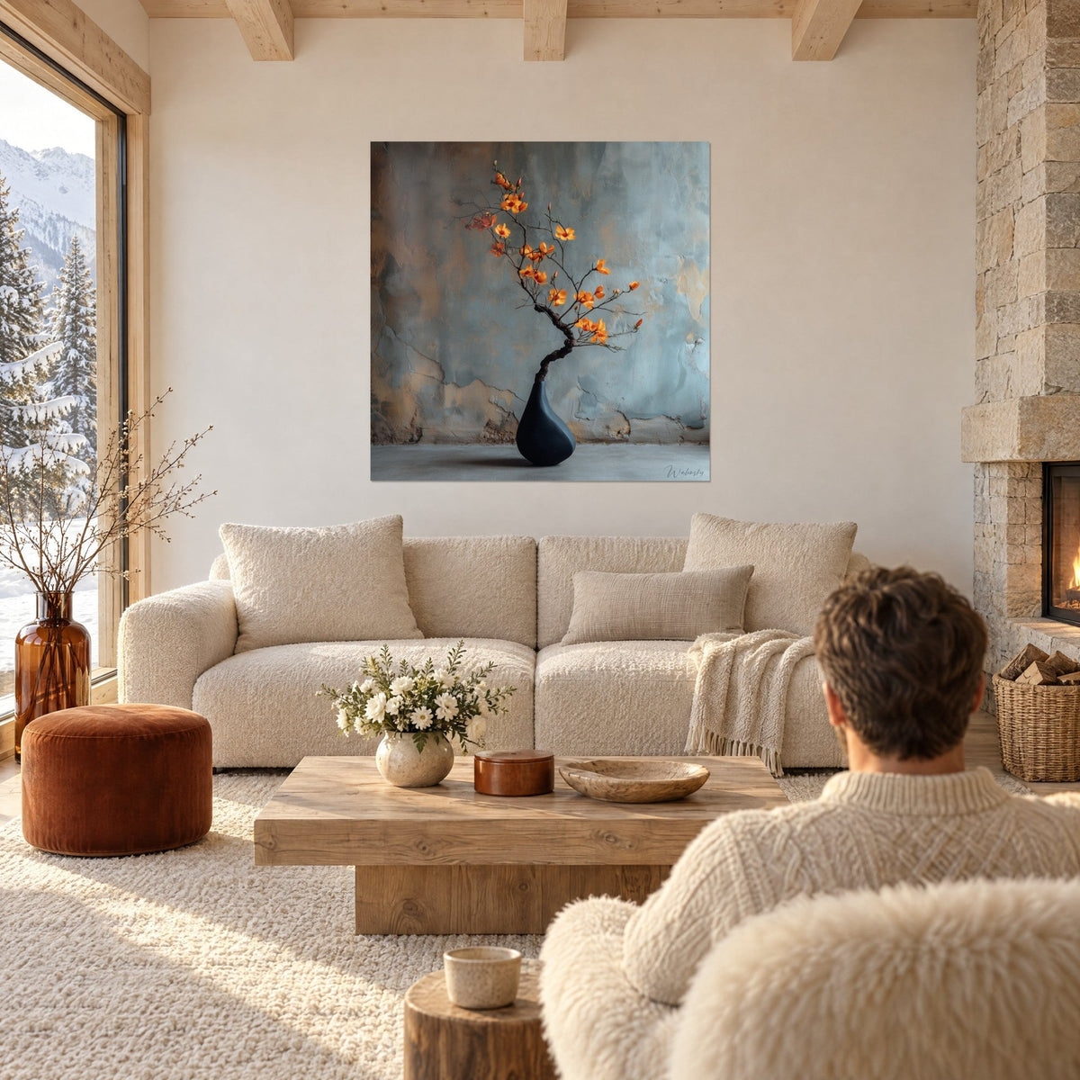 Tableau branche fleurie orange dans un vase bleu marine, mur patiné bleu-gris et ocre, au-dessus d'un canapé dans un salon lumineux