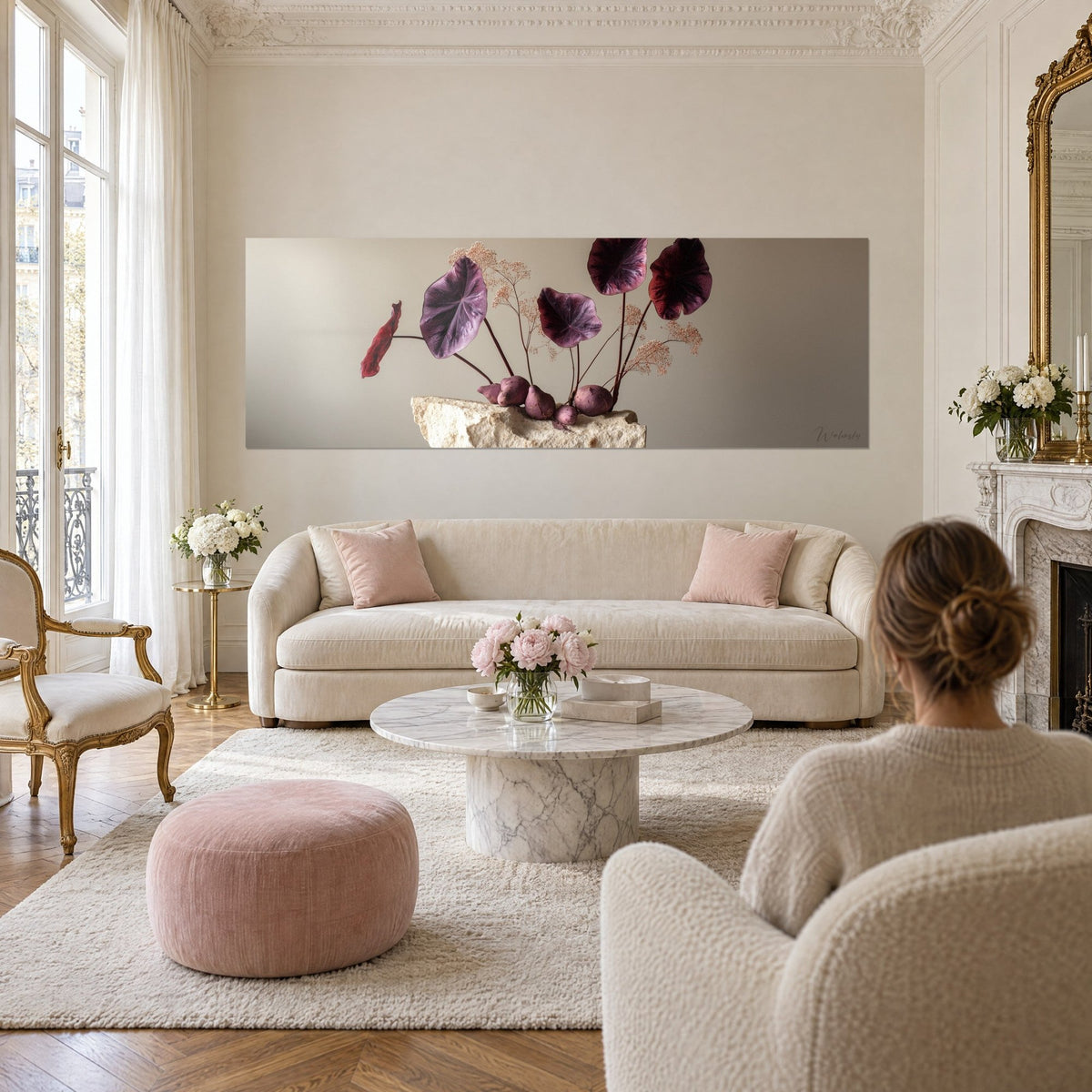 Wall art ikebana with large aubergine leaves on a limestone plinth, taupe background, above a sofa in a bright living room
