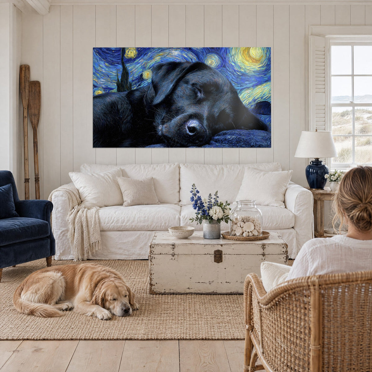 Cuadro de un labrador negro dormido sobre un cielo nocturno estrellado en azul cobalto y amarillo sol, encima de un sofá en un salón luminoso