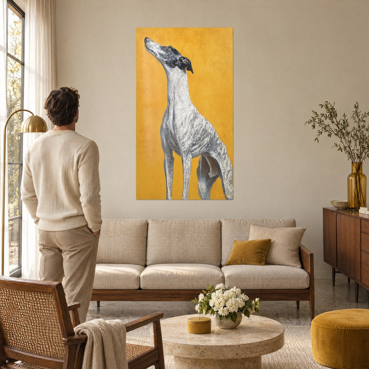Wall art whippet greyhound muzzle raised, white coat speckled with grey on ochre background, man seen from behind above a sofa in a bright living room