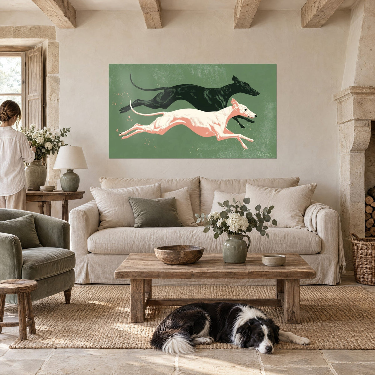 Cuadro galgo negro y whippet blanco rosado lanzados al galope sobre fondo verde salvia, encima de un sofá en un salón luminoso