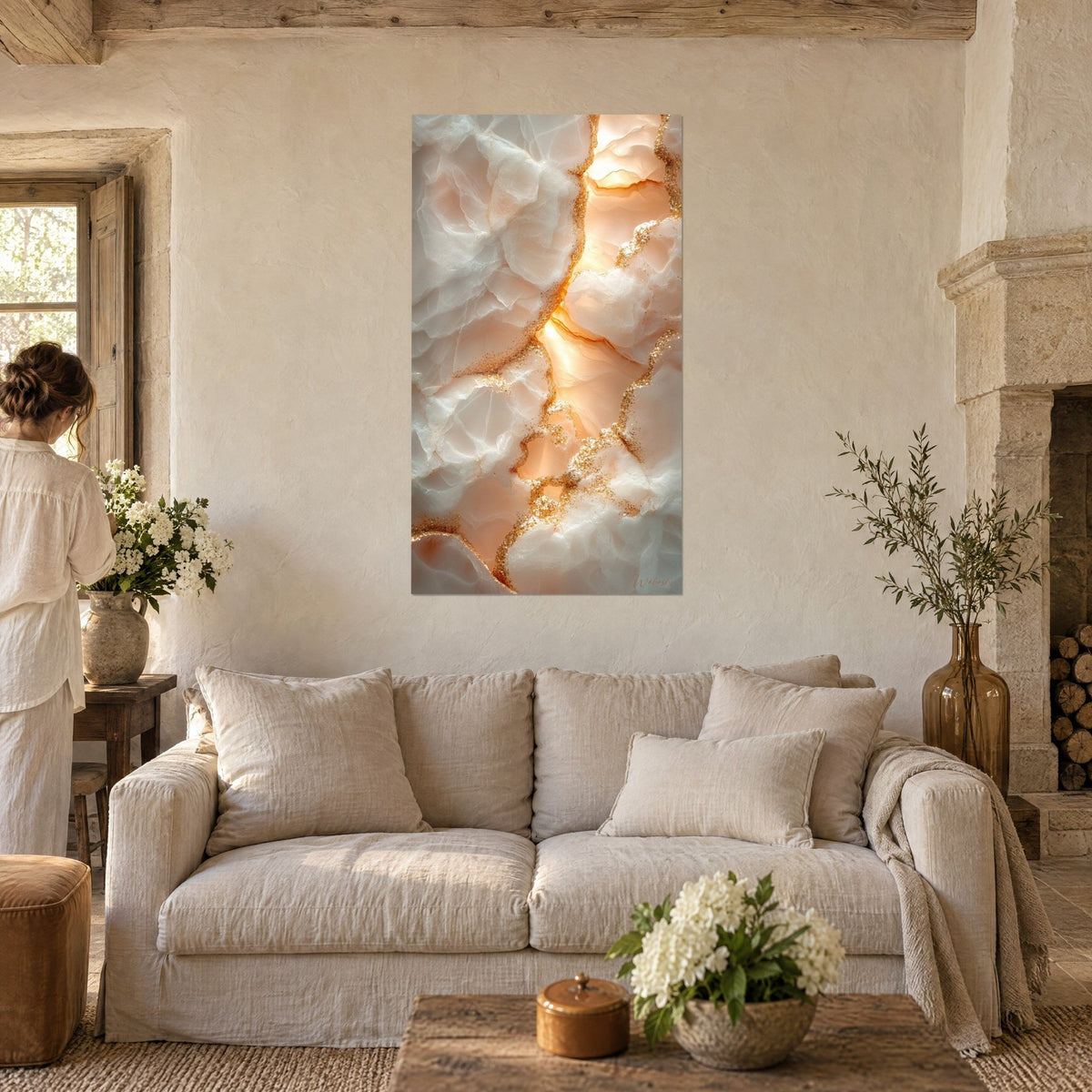 Tableau veines dorées scintillantes sur marbre nacré, rose pêche et blanc, une femme de dos, au-dessus d'un canapé dans un salon lumineux