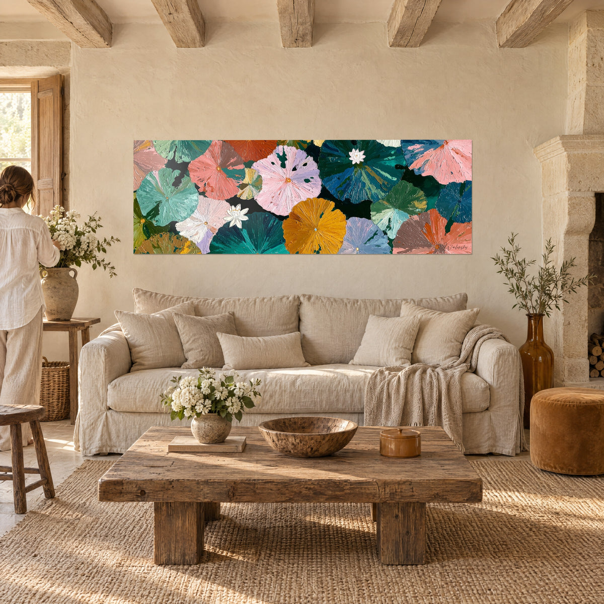 Quadro ninfee in tonalità pastello che galleggiano su uno sfondo smeraldo, rosa e ocra, con due fiori bianchi, sopra un divano in un soggiorno luminoso