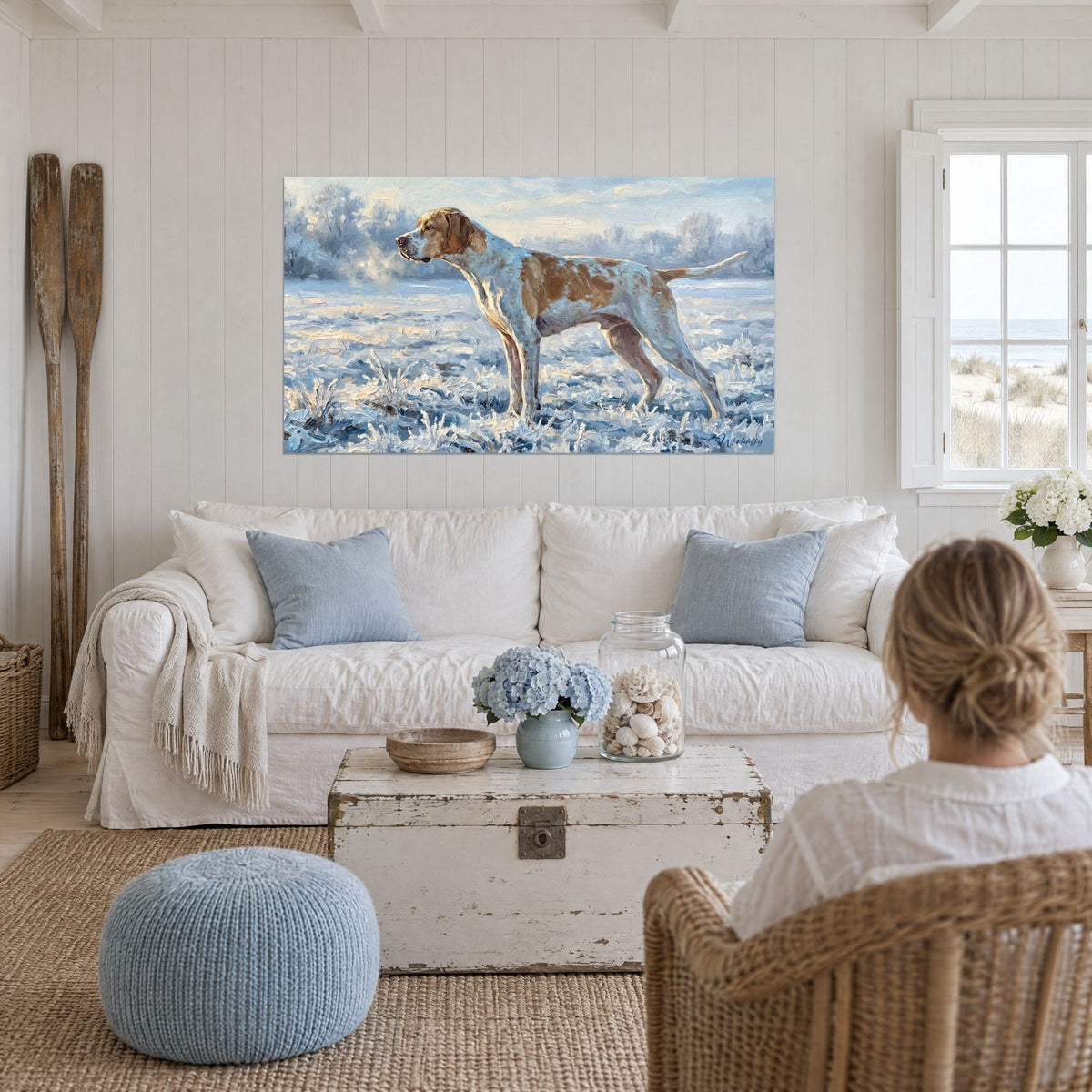 Wall art of an English Pointer with a white and tan coat, frozen in point on a frosty meadow, above a sofa in a bright living room