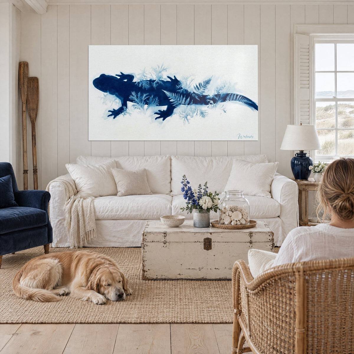 Tableau salamandre bleu nuit ornée de fougères givrées sur fond blanc, retriever couché devant, au-dessus d'un canapé dans un salon lumineux