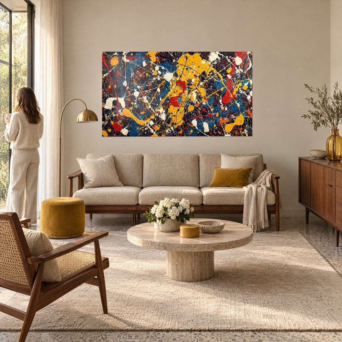 Tableau éclaboussures jaune moutarde et bleu cobalt, giclées blanches sur fond sombre, au-dessus d'un canapé dans un salon lumineux