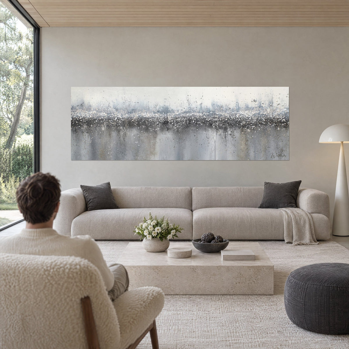Quadro astratto in sfumature di grigio e bianco, riflessi argentati su una fascia scura, sopra un divano in un soggiorno luminoso