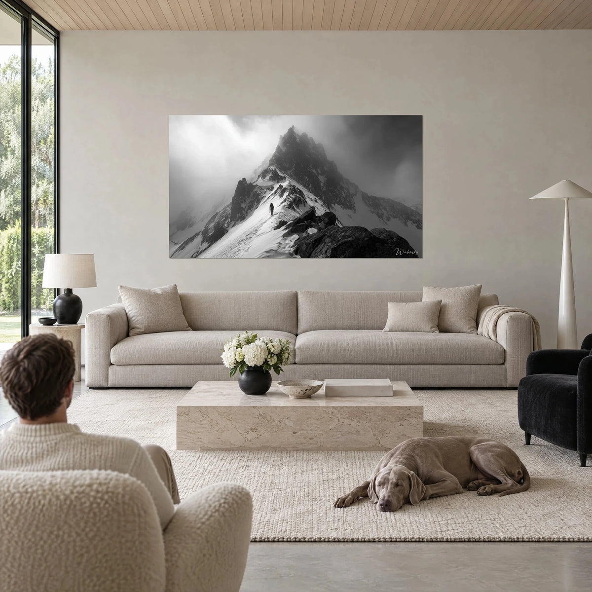 Tableau alpiniste solitaire sur une arête enneigée, ciel de brume gris et noir, Weimaraner couché, au-dessus d'un canapé dans un salon lumineux