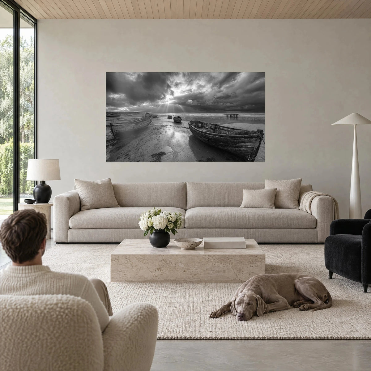 Tableau barques de pêche échouées sous un ciel d'orage gris charbon, rayons blancs sur le sable, au-dessus d'un canapé dans un salon lumineux