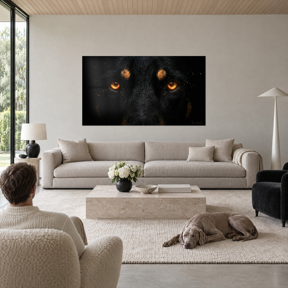 Gemälde Beauceron mit bernsteinfarbenen Augen vor schwarzem Hintergrund, kohlschwarzes Fell, goldene Funken, über einem Sofa in einem hellen Wohnzimmer