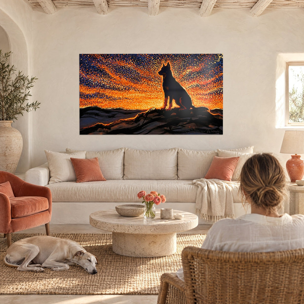 Gemälde Sitzender Hund als indigoblaue Silhouette vor pointillistischem orangefarbenem Himmel, Frau von hinten und Windhund, über einem Sofa in einem hellen Wohnzimmer