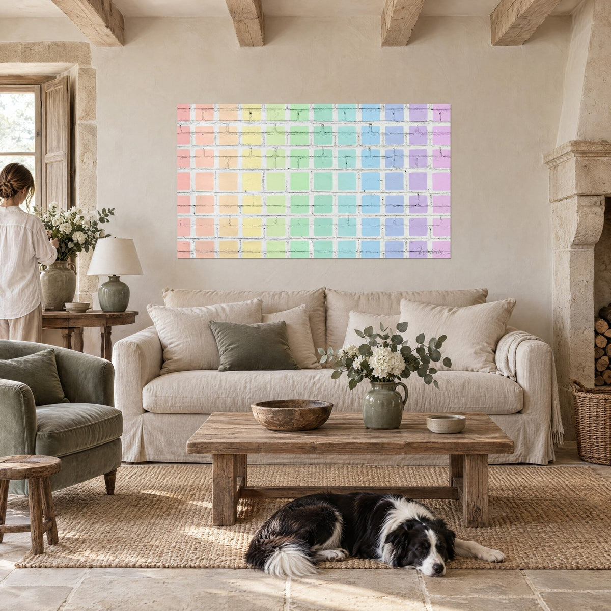Schilderij witgekalkte bakstenen muur met pastelroze, gele en blauwe vierkanten, collie liggend op het kleed, boven een bank in een lichte woonkamer