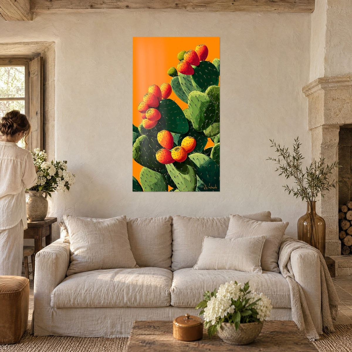 Tableau figuier de Barbarie aux fruits rouges et jaunes sur fond orange vif, raquettes vert sapin, au-dessus d'un canapé dans un salon lumineux