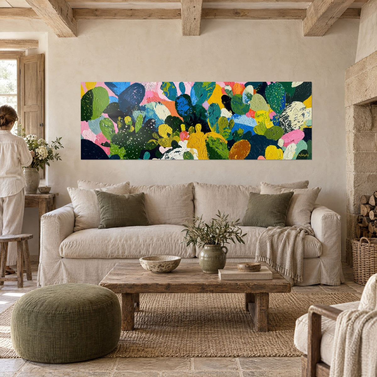 Tableau cactus cubistes jaune moutarde et vert sapin, pâte épaisse et touches roses, silhouette de dos, au-dessus d'un canapé dans un salon lumineux