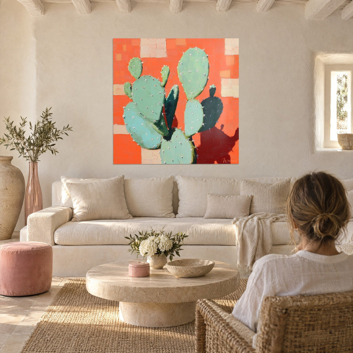Quadro cactus opuntia verde menta su fondo arancione corallo, donna di spalle sopra un divano in un soggiorno luminoso