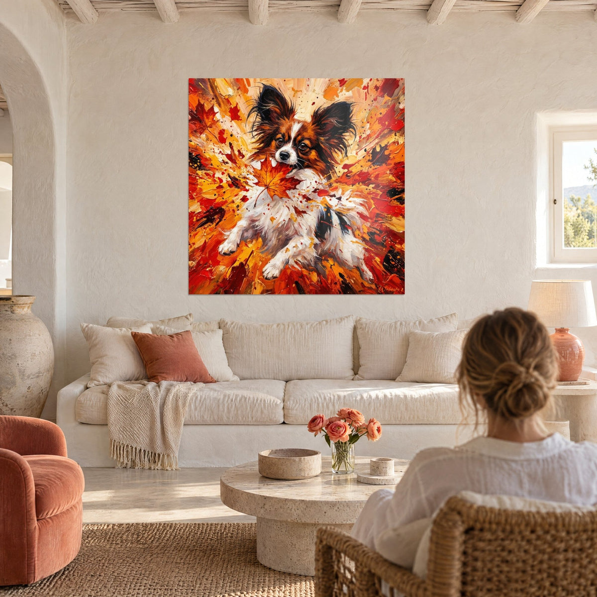 Gemälde Schmetterlingshund mit gefransten Ohren, orangefarbenes Ahornblatt im Maul, rote Farbspritzer, über einem Sofa in einem hellen Wohnzimmer