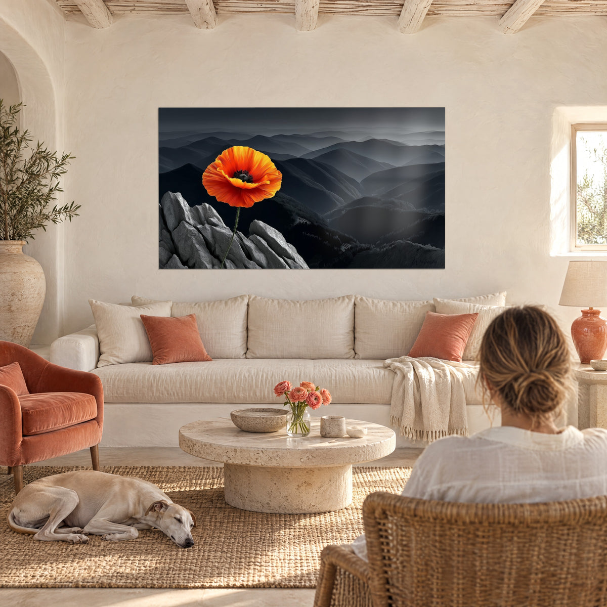 Gemälde Leuchtend orangefarbener Mohn vor grauen Bergen, Paar von hinten und liegender Windhund, über einem Sofa in einem hellen Wohnzimmer