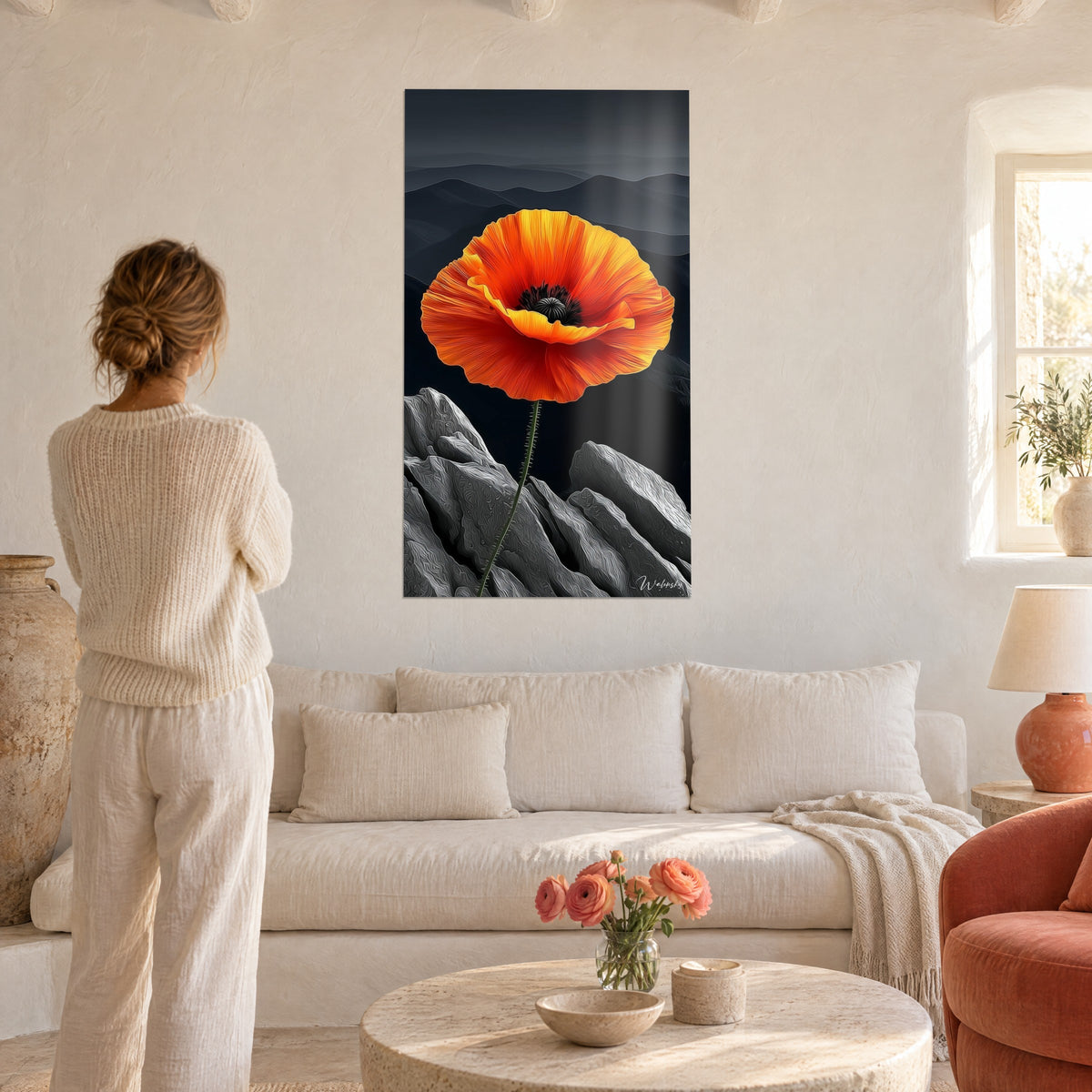 Schilderij klaproos in oranje en geel met gekreukte bloemblaadjes voor grijze bergen, vrouw van achteren, boven een bank in een lichte woonkamer
