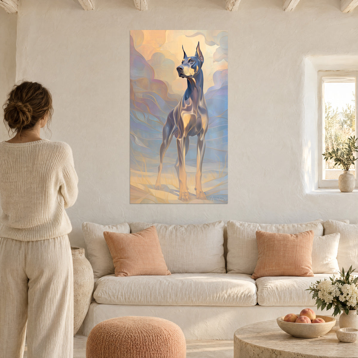 Schilderij dobermann met rechtopstaande oren, leigrijsblauwe vacht met gouden glans, vrouw van achteren, boven een bank in een lichte woonkamer