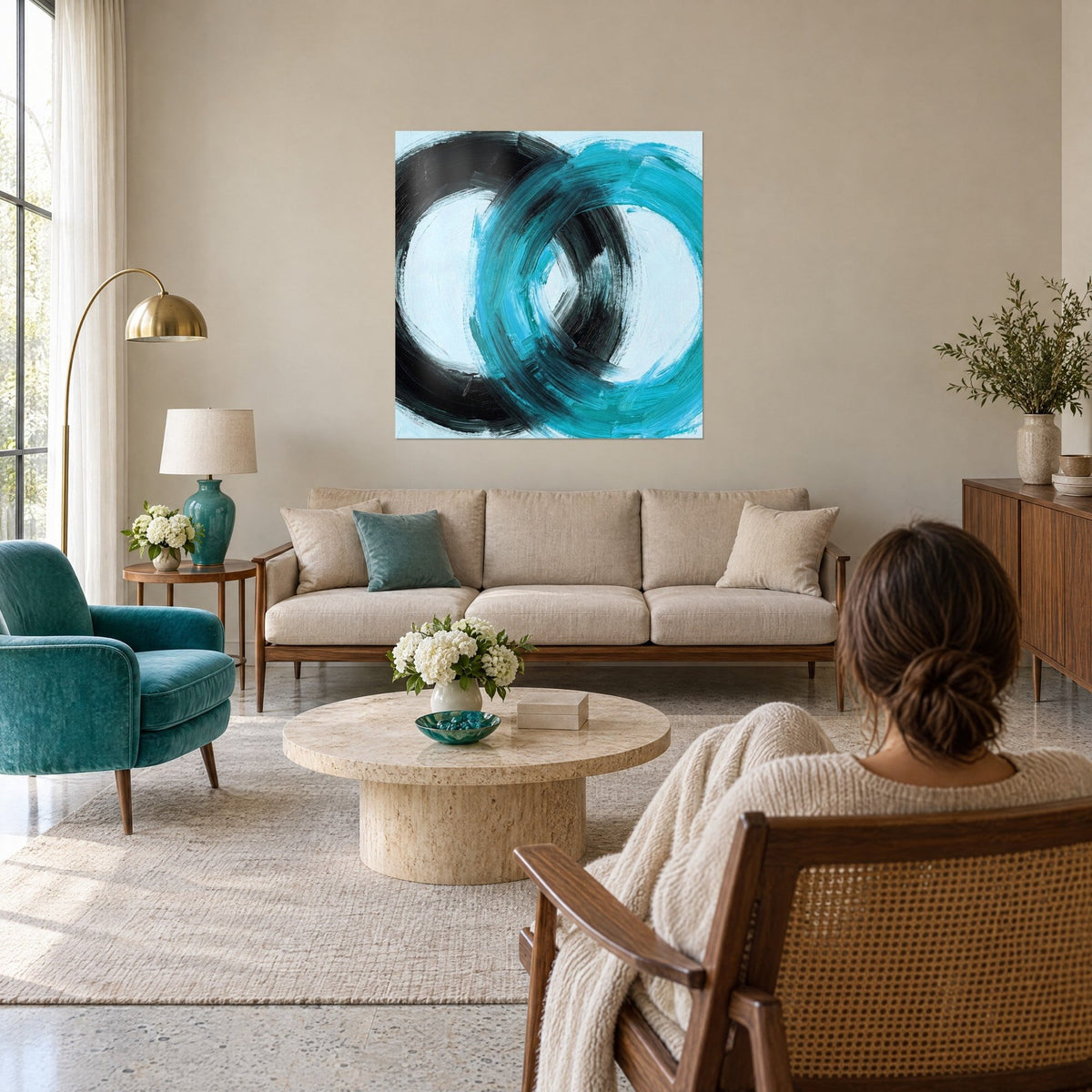 Tableau anneaux entrelacés en coups de brosse turquoise et noirs sur fond bleu glacé, au-dessus d'un canapé dans un salon lumineux