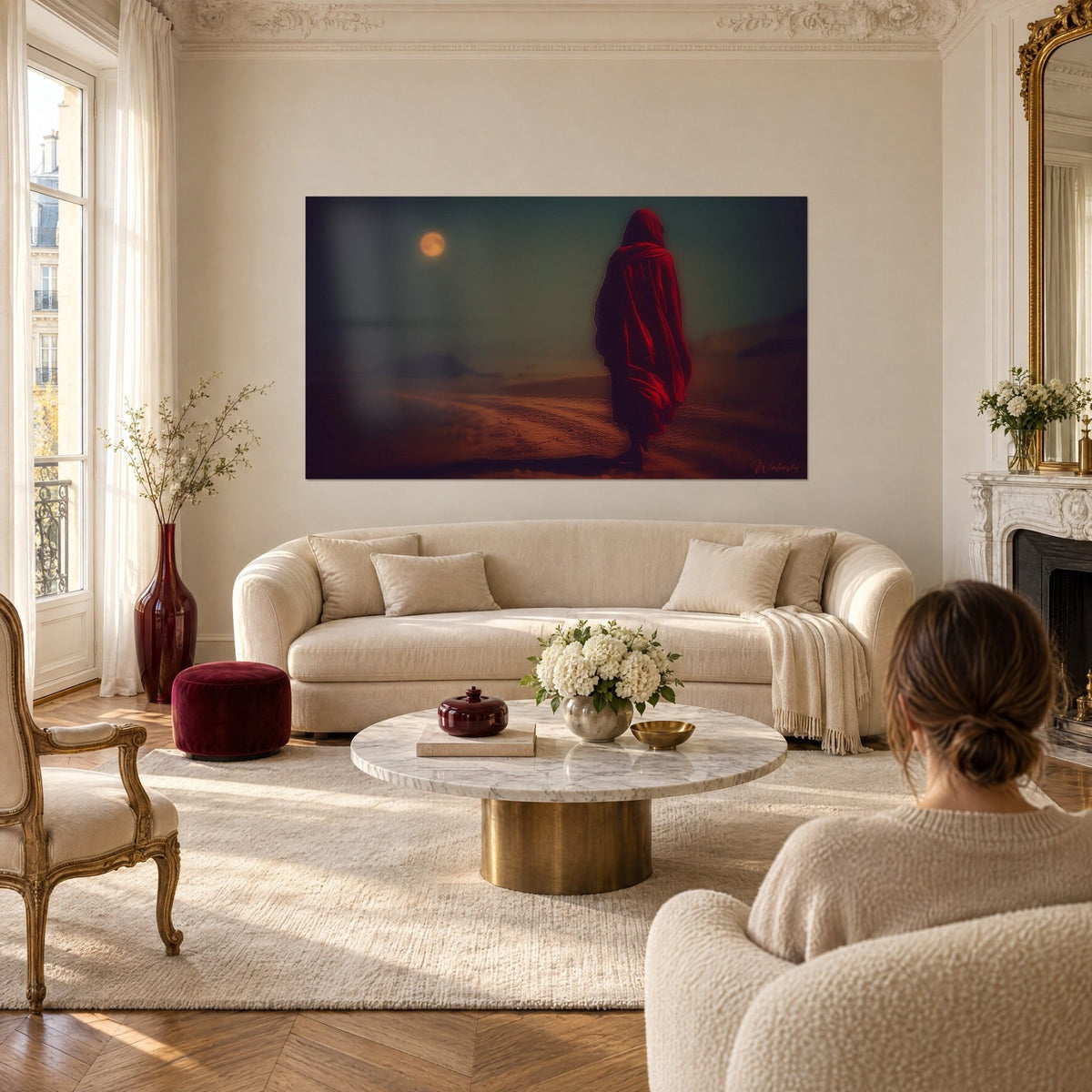 Wall art of a silhouette draped in red beneath an orange moon, ochre sand, dark green sky, above a sofa in a bright living room