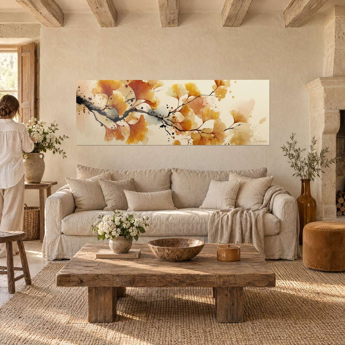 Schilderij ginkgotak met gouden en oranje bladeren op beige achtergrond, zwarte inktstam, boven een bank in een lichte woonkamer