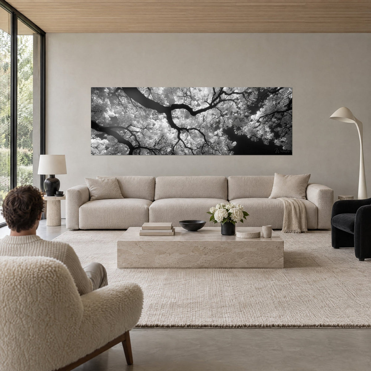 Tableau ramure de ginkgo en noir et blanc, feuillage blanc éclatant, branches d'ébène, au-dessus d'un canapé dans un salon lumineux