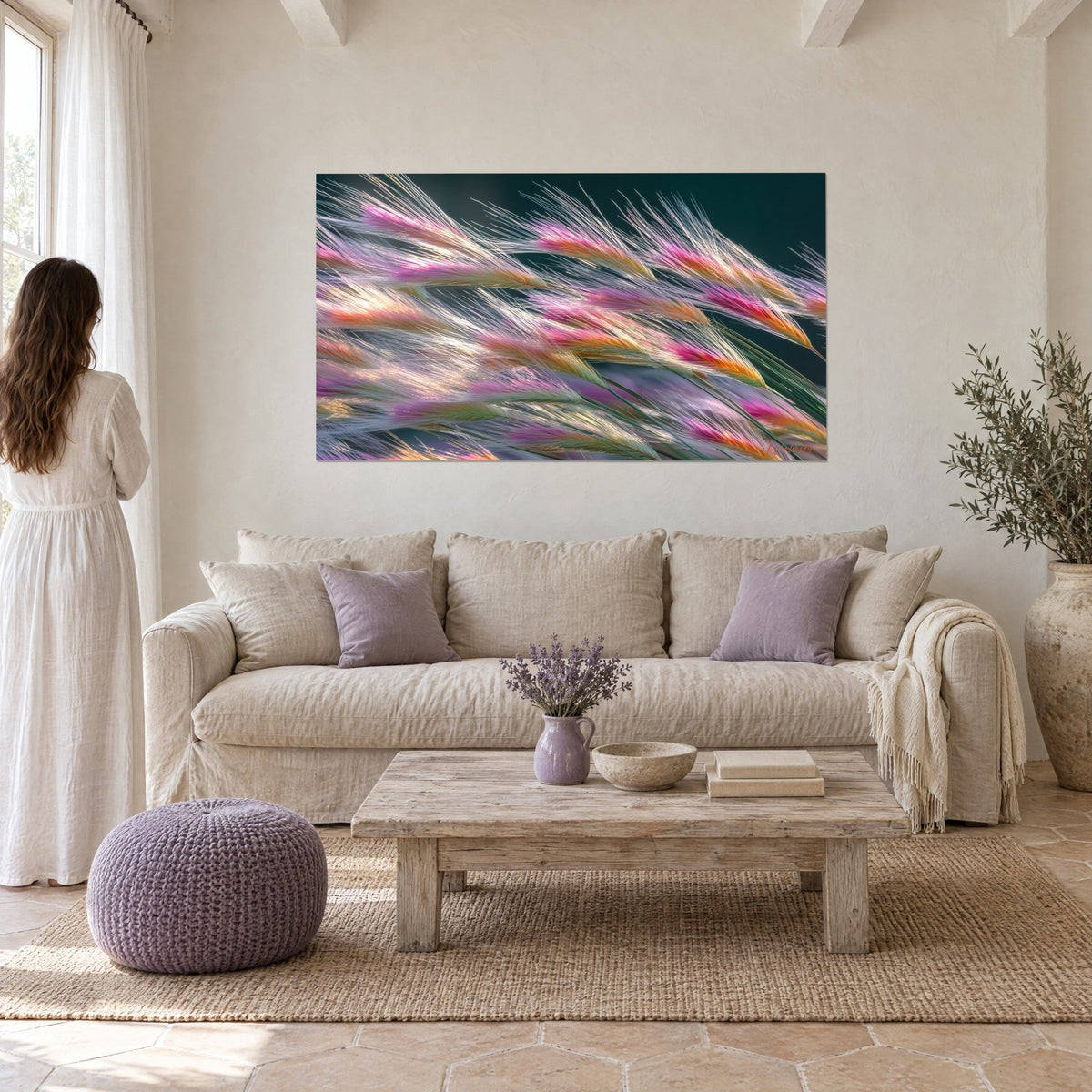 Tableau épis duveteux aux pointes rose fuchsia et orange, fond vert sombre, femme de dos, au-dessus d'un canapé dans un salon lumineux