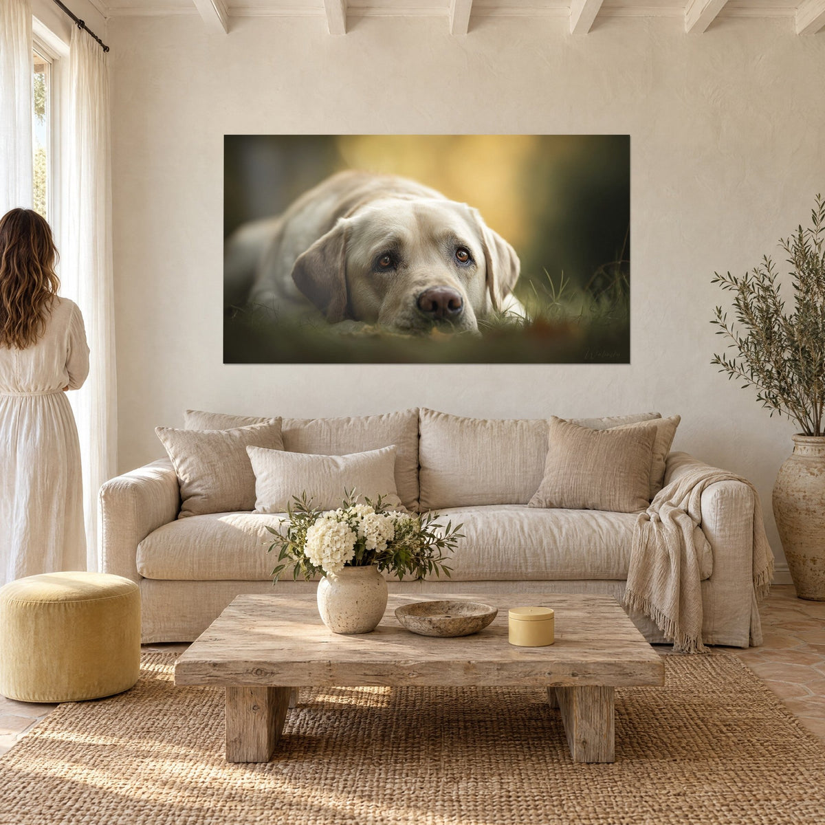 Gemälde Labrador cremefarben, rosa Schnauze im grünen Gras vor goldenem Hintergrund, eine Frau von hinten, über einem Sofa in einem hellen Wohnzimmer