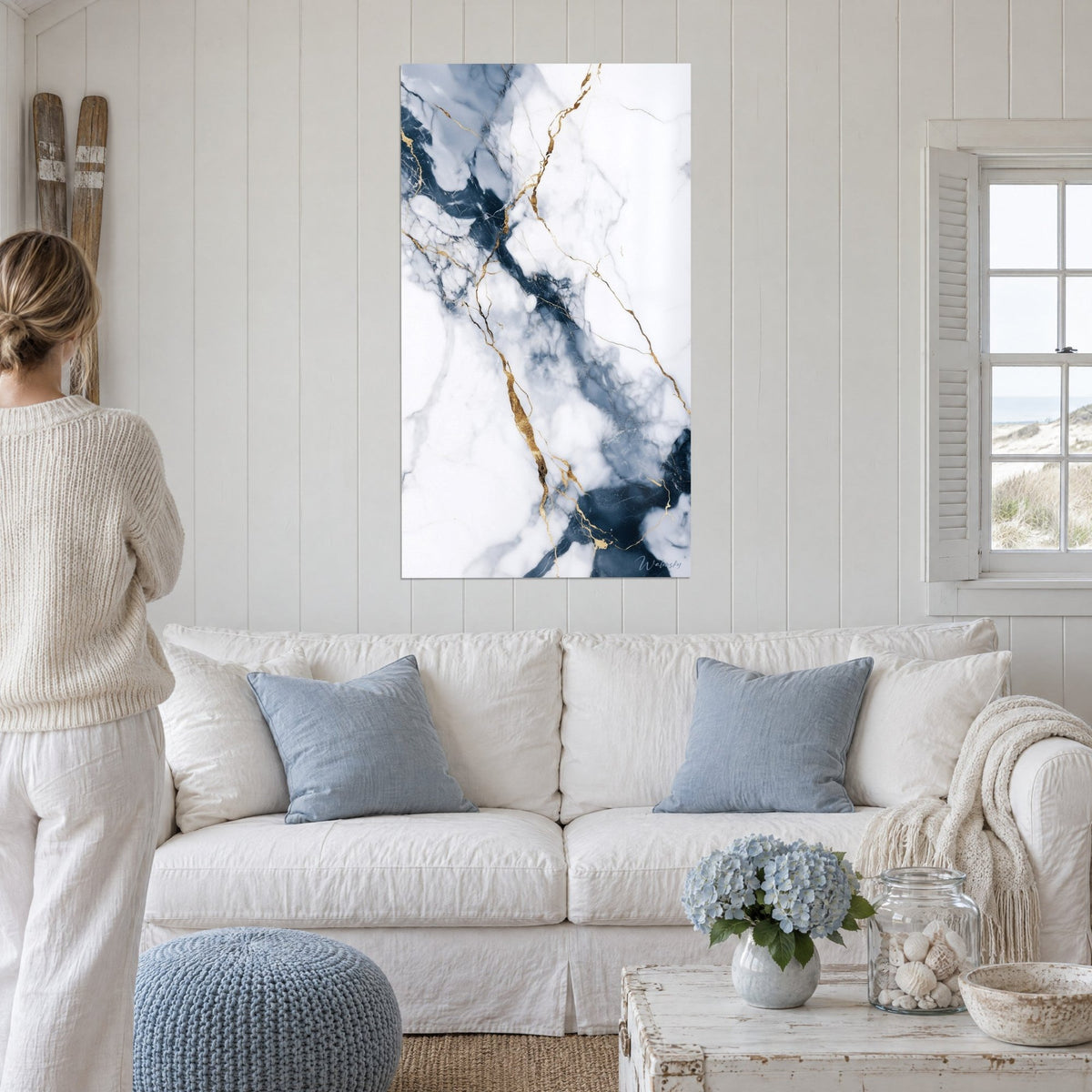 Tableau marbre blanc veiné de bleu nuit et de filets dorés, accroché au-dessus d'un canapé dans un salon lumineux
