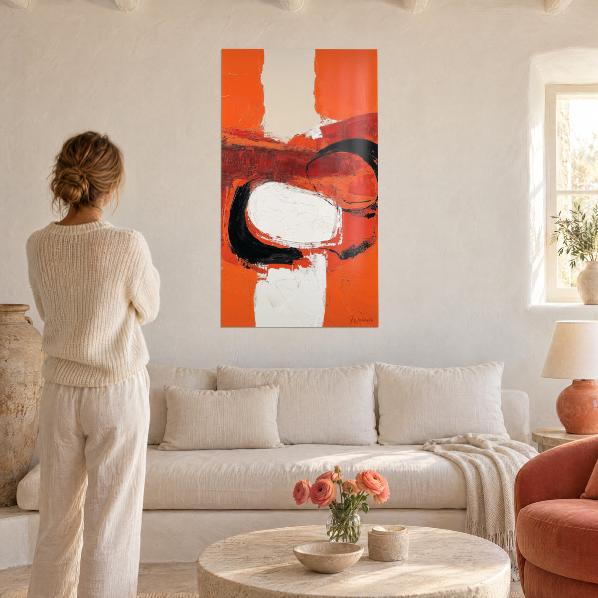Quadro astratto arancione vivace con campiture bianche e arco nero, donna di spalle sopra un divano in un soggiorno luminoso