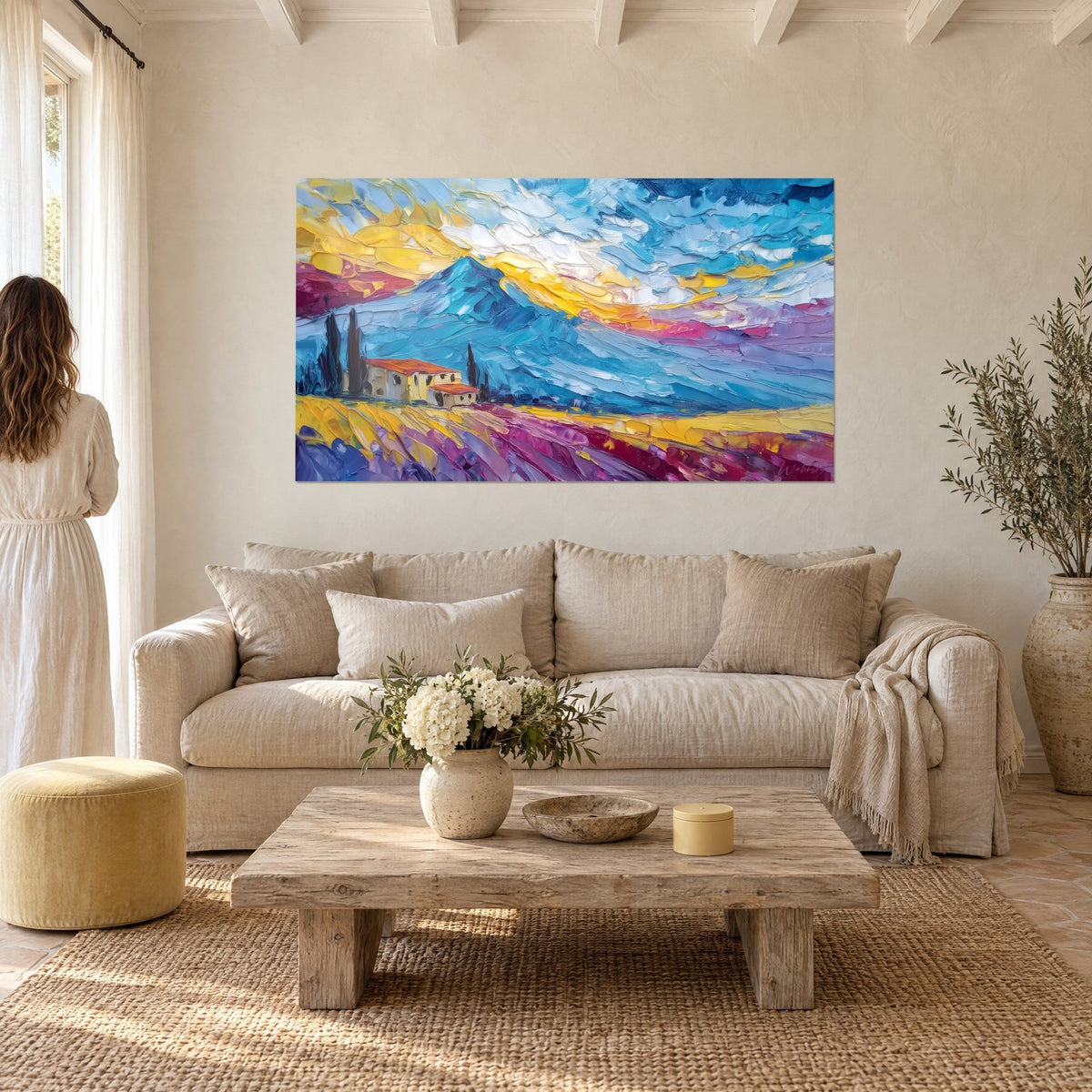 Gemälde Bauernhaus mit orangefarbenen Dächern unter einem türkisblauen Vulkan, gelber und rosafarbener Himmel in pastoser Malweise, über einem Sofa in einem hellen Wohnzimmer